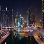 Crowds celebrating New Year with fireworks and illuminated boats along Dubai Marina.